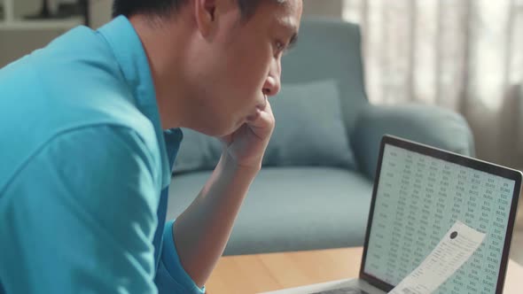 Close Up Of Asian Man With A Laptop Looking At The Bill And Having Headache Due To Financial Problem