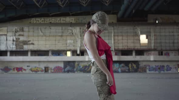 Attractive Young Woman in Military Uniform Trying on Red Dress and Dancing Around, Smiling