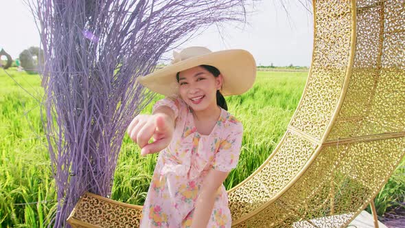 Portrait of Asian adult woman relaxing near big rice field.