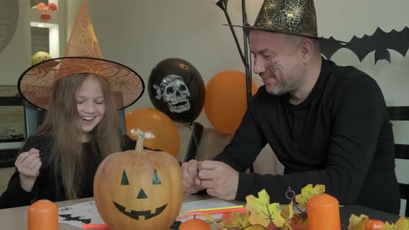 Child with Father Draw Pictures on the Theme of Halloween in Decorated Room at Home