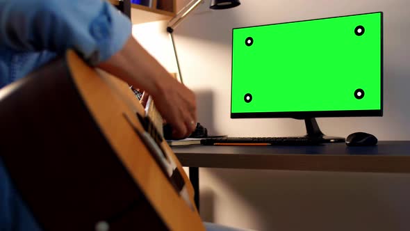 Young Man with Music Book Playing Guitar at Home