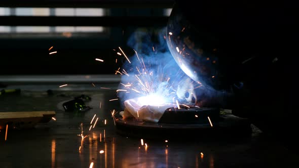 Industrial Worker in Protective Mask Using Modern Welding Machine for Welding Metal Construction