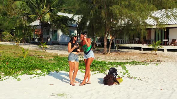 Ladies together enjoying life on paradise tourist beach adventure by aqua blue lagoon and white sand