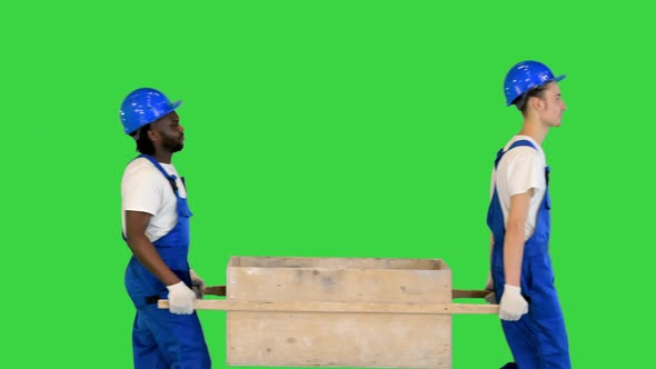 Two Construction Workers Carrying a Handbarrow on a Green Screen Chroma Key