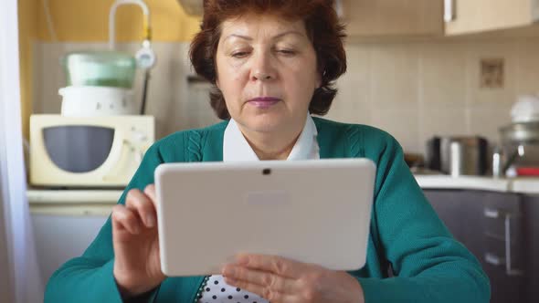 Portrait Of A Mature Woman Is Using A White Tablet Pc At Home