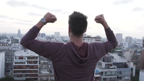 Rear view of man stretching his hands while looking at cityscape