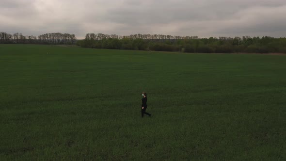 Woman Walking Across a Green Field in a Protective Mask From Viruses Pandemic Covid19 Drone View