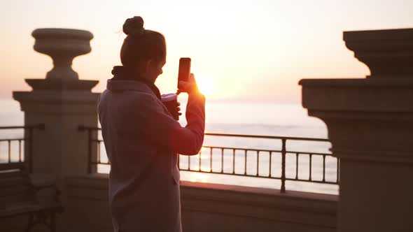 Young Lady Making Photo of Sea at Sunrise on Smartphone in Slowmotion