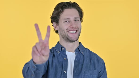 Victory Sign By Successful Young Man on Yellow Background