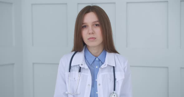 Female Retiree Doctor Is Consulting Online, Looking at Camera and Nodding, Listening By Headphones