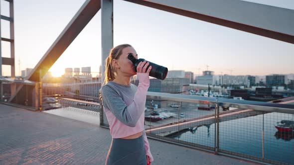 Young Female Stand on Bridge Drink Water Tired After Training