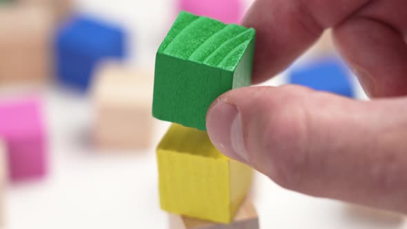 Assembling a toy colored wooden block tower with multicolored cubes