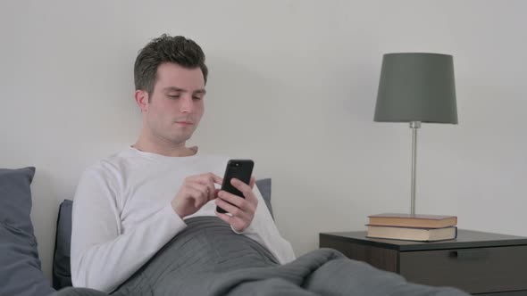 Man Using Smartphone in Bed