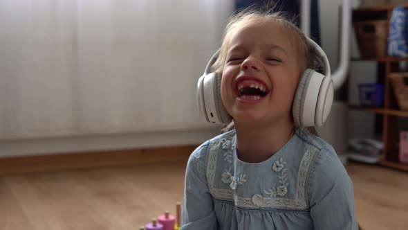 Child Listening Music In Big White Headphones