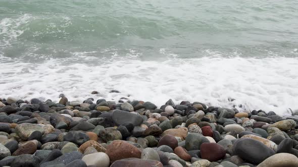 Sea Waves Roll on Pebbles Shore During a Light Storm Close Up