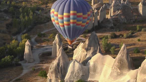 Large Hot Air Balloon Flies Over Bare Rocky Stone Pillars