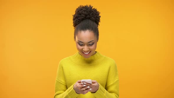 Smiling African-American Woman Chatting on Smartphone and Showing Ok Gesture