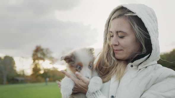 The Owner of the Puppy Holds the Pet in His Arms