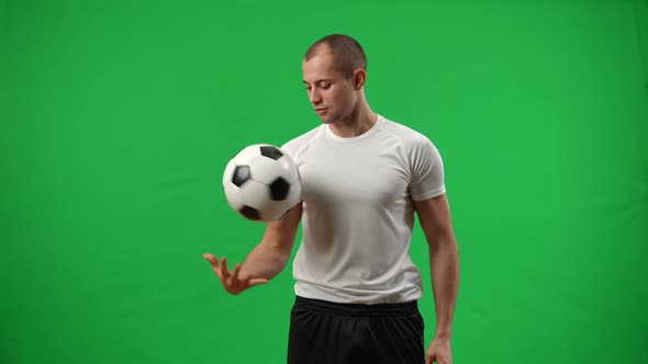 Smiling Young Footballer Passing Ball From Head to Hand Looking Away Standing on Green Screen