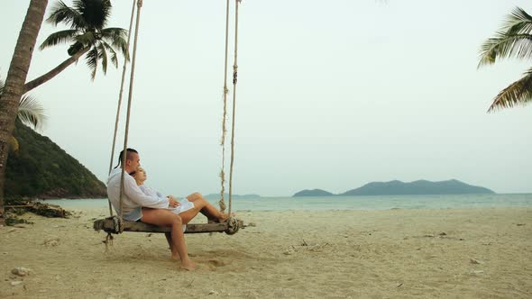 Loving Couple on the Swing on Tropical Beach