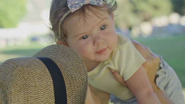 Closeup of Beautiful Baby As Her Mother Holds Her Up High at Park