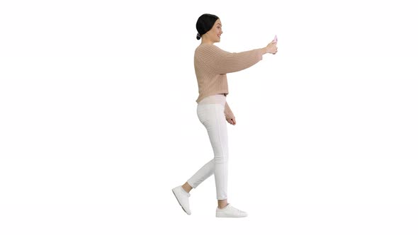 Smiling and Gesturing Young Woman Having Video Call on Her Phone While Walking on White Background.