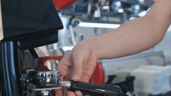 Coffee grinder grinding freshly roasted coffee beans into