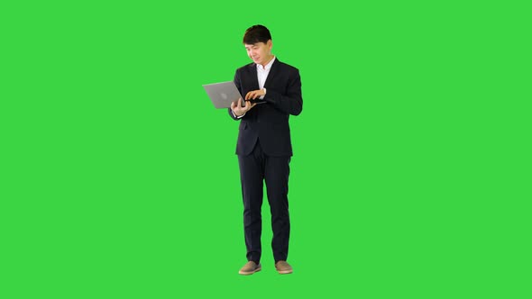 Asian Man Working with Laptop on a Green Screen Chroma Key