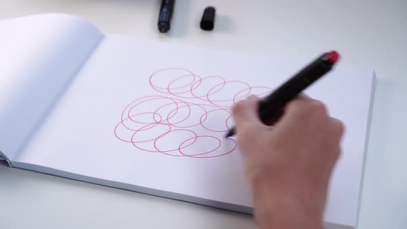 Hand of a teenager draws with felt-tip pen on a white blank sheet of an album