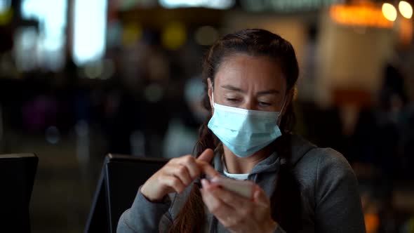 Woman with Facial Mask Is Using Smartphone in Public Place, Browsing Social Nets