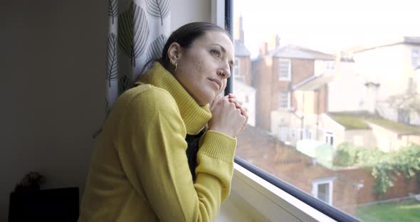 Woman at home looking out of the window and enjoying the view, planning futur