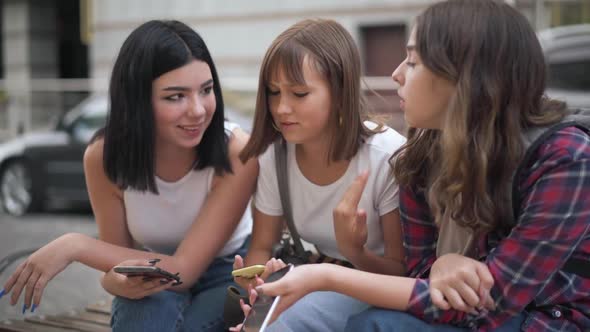 Cheerful Caucasian Teenage Female Friends Gossiping Surfing Social Media in Smartphone App Talking