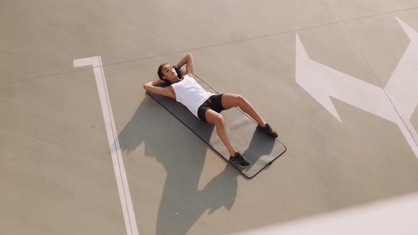 A top view of a calm american woman wearing sport-suit doing exercises on a yoga mat