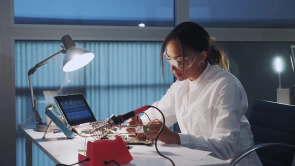 Middle Close Up of African American Electronics Engineer in Protective Glasses Checking Motherboard