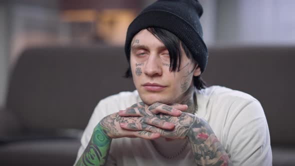 Portrait of Man with Tattooed Face and Hands Turning Looking at Camera with Thoughtful Facial