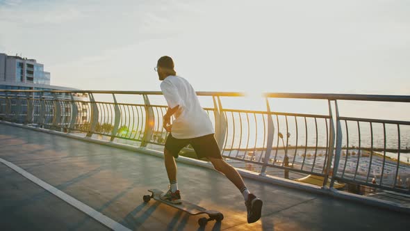 Young Man Practicing Skateboarding on City Bridge Enjoying Sunset