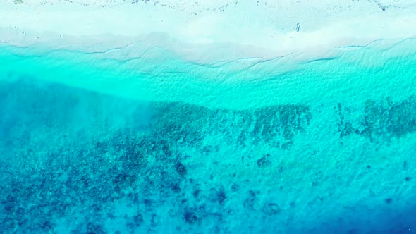 Aerial flying over scenery of idyllic seashore beach holiday by blue lagoon and white sandy backgrou