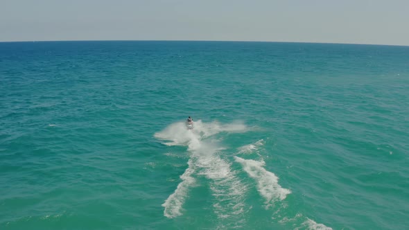 Aerial Drone Following Shot of a Couple on a Ski Jet Driving Through Waves