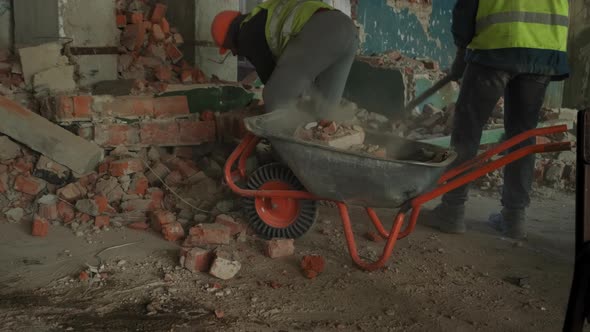 The Worker Uses a Wheelbarrow to Remove Construction Debris