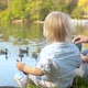 A young mother and her son are feeding the ducks on a lake - VideoHive Item for Sale