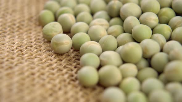 Dry green peas on rustic burlap. Macro. Dried whole beans