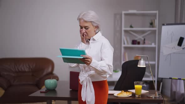 Stressed Troubled Middle Aged Businesswoman Standing with Tablet in Office Getting Bad News