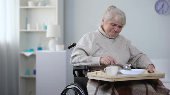 Capricious Old Lady in Wheelchair Asking Nurse Taking Away Unappetizing Dinner