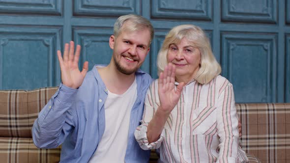 Family of Senior Grayhaired Mother and Handsome Adult Son or Grandson Waving Hi Hello Welcome