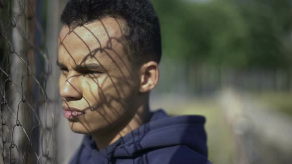 Afro-American Boy Watching Rich District Through Fence, Poverty, Immigration