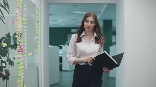 Employee Goes Around the Office with a Folder of Papers in His Hands. Young Woman in Business