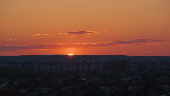 Evening Landscape with Bright Setting Sun Over Distant City High Rise Buildings at Sunset