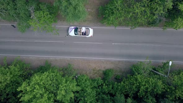 Vertical Round Motion Over Wedding Couple in Convertible