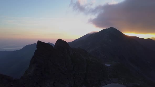 Deep shadows on rugged landscape of mountains as evening light fades. Purple, blue, pink shy horizon