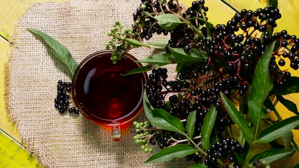 Close Up Red Black Berry Tea In A Cup Top View On A Wooden Vintage Table. Elderberry Tea. Vitamins